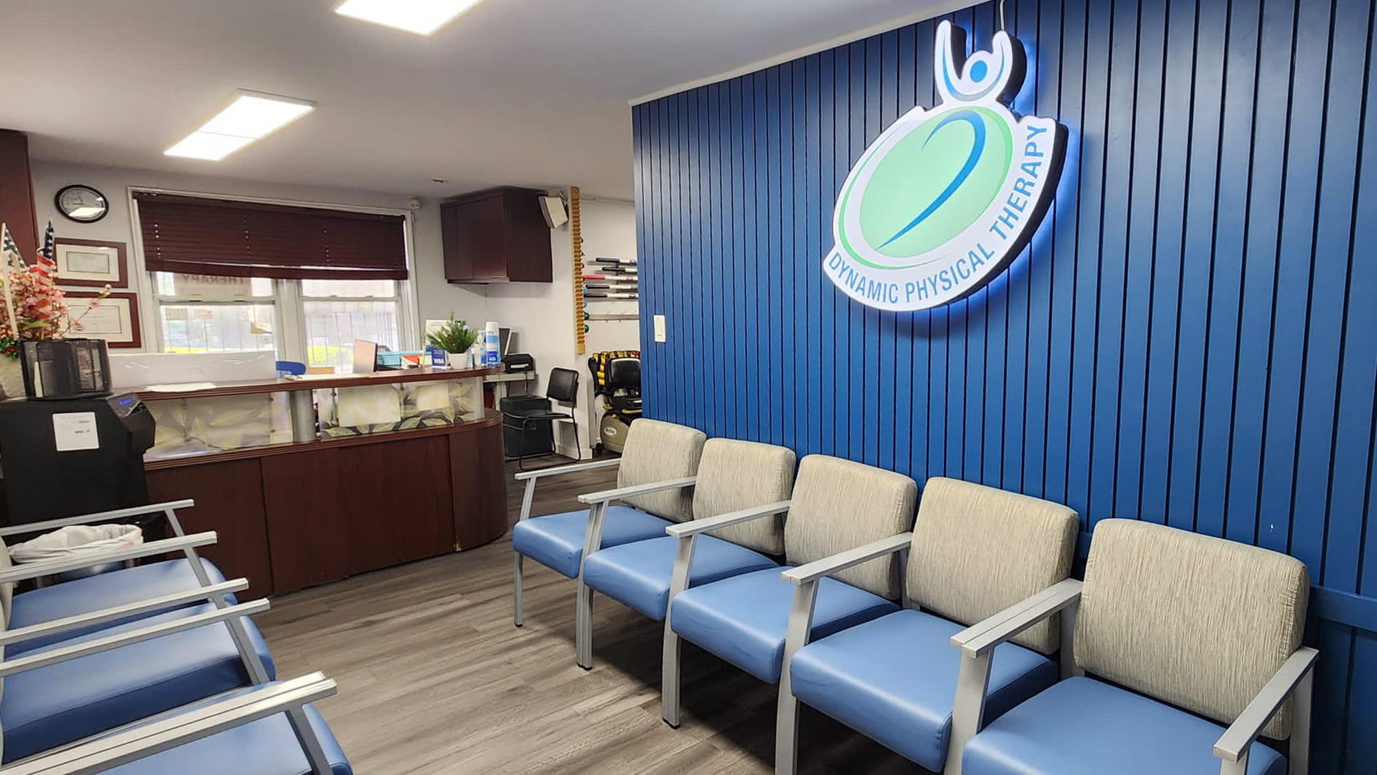 Flushing clinic reception desk and waiting room with the illuminated Dynamic Physical Therapy sign