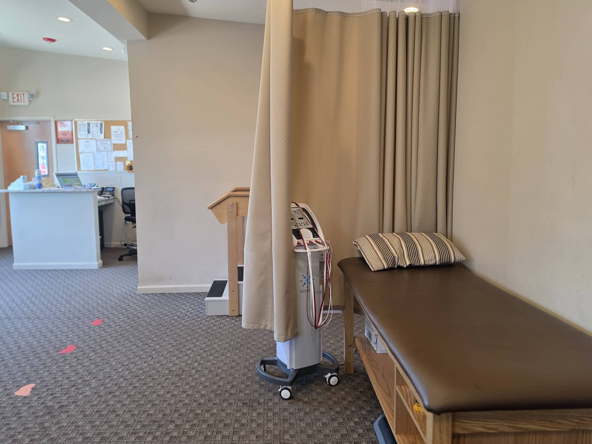 Massapequa clinic treatment bay with privacy curtain and reception in view
